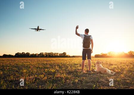 Saying hello at the sunset. Young man with his dog on the evening walk along the airport. Stock Photo