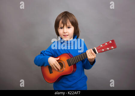 Preschool child, playing little guitar, isolated image, studio shot Stock Photo