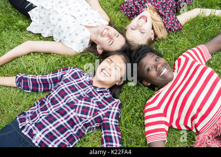 Overhead View Of Teenage Girl Friends Lying In Grass Stock Photo