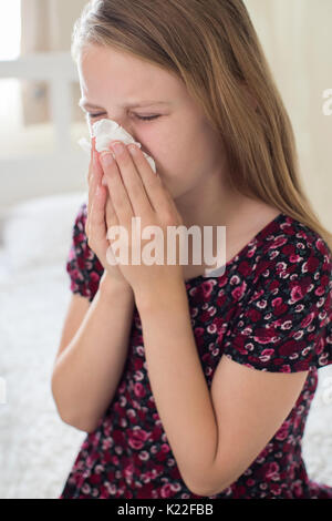 Girl Suffering With Cold Sneezing Into Tissue Stock Photo
