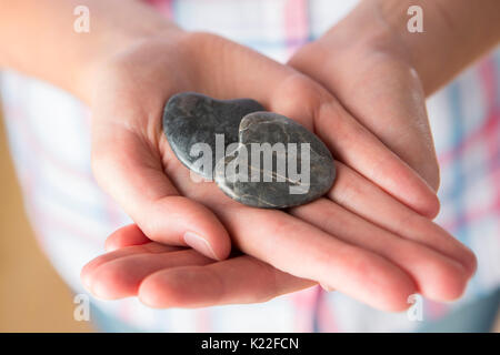 Close Up Of Hand Holding Two Heart Shaped Stones Stock Photo