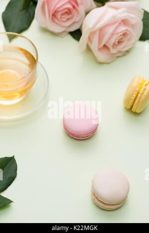 French macaroons. Many variegated sweet macarons in box with bouquet of pink roses on the table Stock Photo
