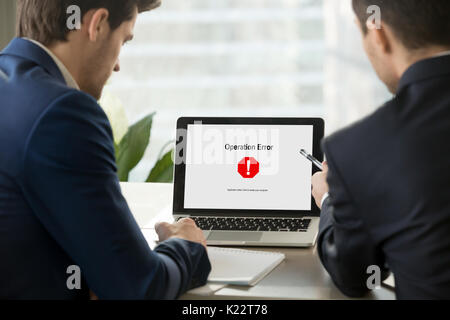 Two businessmen looking at broken laptop, operating system crash Stock Photo