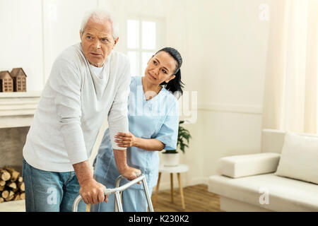 Pleasant professional caregiver holding her patients hand Stock Photo