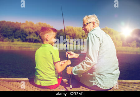 grandfather and grandson fishing on river berth Stock Photo