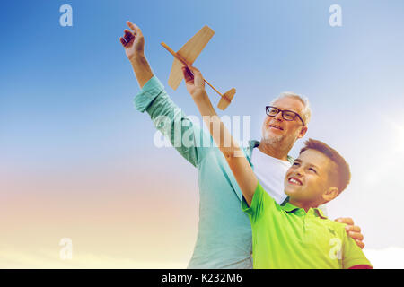 senior man and boy with toy airplane over sky Stock Photo