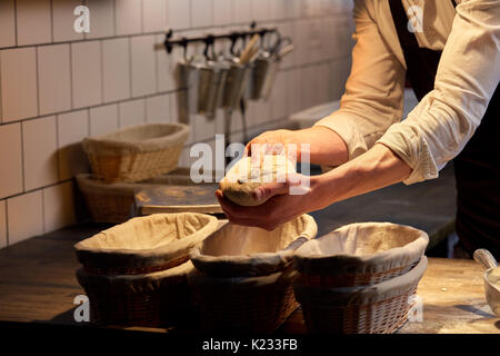 baker with dough rising in baskets at bakery Stock Photo