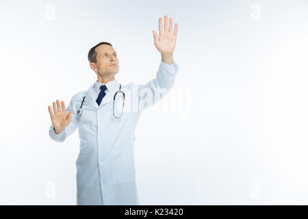 Mature male doctor trying to touch invisible screen Stock Photo