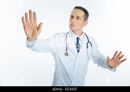 Male physician with stethoscope touching invisible screen Stock Photo