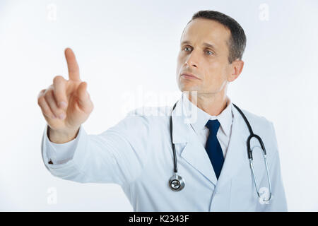 Serious mature doctor using invisible touchscreen alone Stock Photo