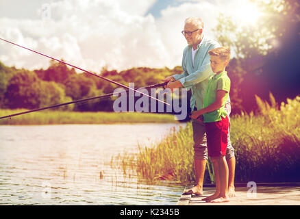grandfather and grandson fishing on river berth Stock Photo