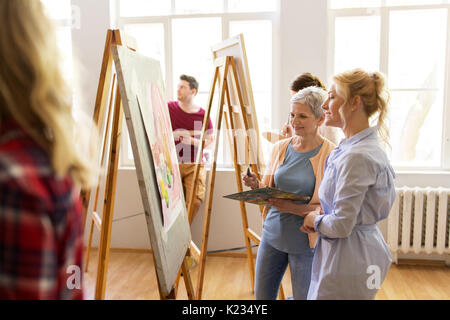 woman artist with easel painting at art studio Stock Photo by dolgachov