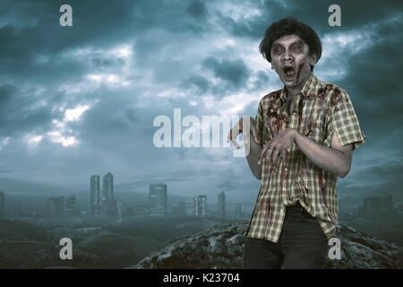 Scary asian zombie man with open mouth standing with dramatic sky background Stock Photo