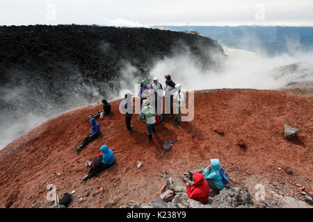 Large group of tourists and travelers rests in crater of active Avachinsky Volcano after hours of climbing to the top of volcano on Kamchatka. Stock Photo