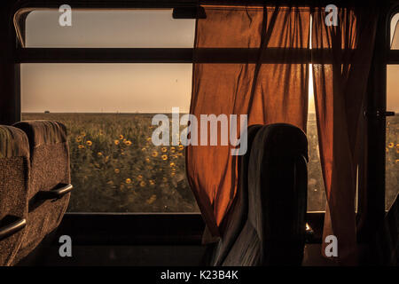 Empty bus seat taken in an old vintage coach during sunset, a field can be seen in the background  Picture of an empty coach seat taken during a journ Stock Photo