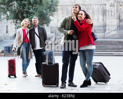 Tourists in casual with baggage stroll along the streets outdoors Stock Photo