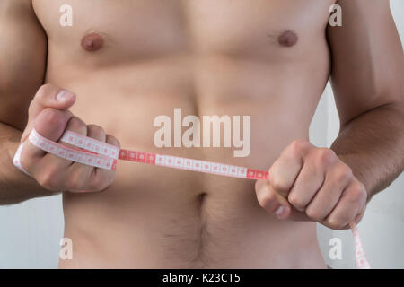 Image of muscular man measure his waist with measuring tape in centimeters  Stock Photo - Alamy