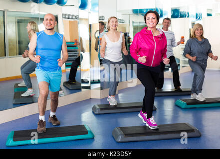Mature men and women training in  gym with dumbbells. Selective focus Stock Photo