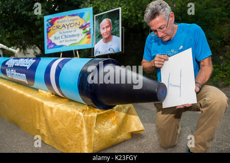 New York, US. 27th Aug, 2017. The world record holder of the Guinness World Records, Ashrita Furman (62), presents the world's largest crayon in the district of Queens in New York, US, 27 August 2017. It is 5.22 metres long and 46 centimetres thick and weighs around 900 kilos. Furman presented the blue crayon in honour of his spiritual teacher Sri Chinmoy (1931-2007) on the occasion of his 86th birhtday. · NO WIRE SERVICE · Photo: Jowan Gauthier/spontaneousbeauty.com/dpa/Alamy Live News Stock Photo