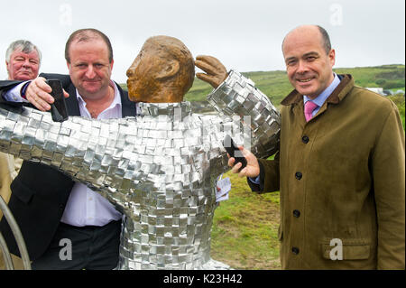 Galley Cove, Ireland. 28th Aug, 2017. Communications Minister Denis Naughten and Deputy Michael Collins TD with Cllr. Joe Carroll looking on, show how far communications have progressed on the ocassion of the unveiling of a statue of Guglielmo Marconi who pioneered long distance radio communications.  Credit: AG News/Alamy Live News. Stock Photo
