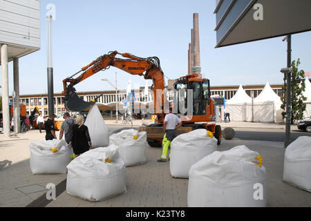 Wolfsburg, Germany. 30th Aug, 2017. An excavator transports sand filled plastic bags, to be used as truck barriers at Goethe Street in front of the Schiller Gallery in Wolfsburg, Germany, 30 August 2017. The city will be the host to more than 300,000 visitors awaited for the 'Day of Lower Saxonians' (1st - 3rd September 2017). The security measures have been tightened visibly comparing to previous years. Photo: Matthias Leitzke/dpa/Alamy Live News Stock Photo