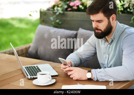 Bearded Businessman using Smartphone in Cafe Outdoors Stock Photo