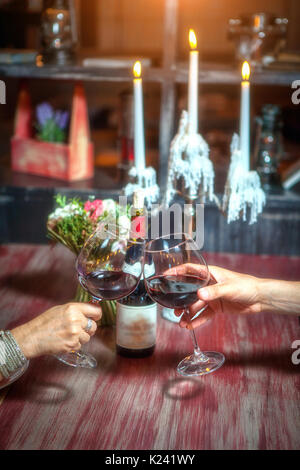 romantic couple with glasses of red wine on a date in a cozy Italian restaurant. Leisure, drinks, people and holidays concept - happy man and woman clinking glasses. Stock Photo