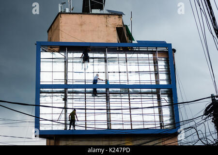 PATAN, NEPAL - CIRCA JULY 2017: Men working on a billboard with menacing monsoon cloud in the background. Stock Photo