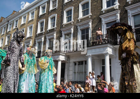 London, UK. 28th August, 2017. Costumed stilt walkers take part in the parade for the Notting Hill Carnival. This year's event, attended by hundreds of thousands of people, took on added significance because of its proximity to the Grenfell Tower and a minute's silence was observed at 3pm. Credit: Mark Kerrison/Alamy Live News Stock Photo