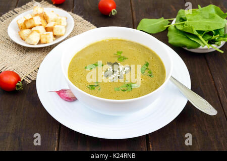 Vegetable cream soup with spinach and potatoes in a white bowl with garlic croutons on a dark wooden background. Dietary vegetarian menu. Proper nutri Stock Photo