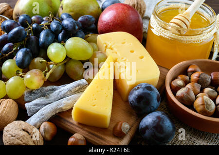 Autumn set of products: grapes, walnuts, hazelnuts, plums, honey, cheese, raisins, pears, dried cranberries on a wooden background Stock Photo