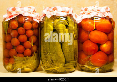 Three Canned Fresh Vegetables. Tomatoes Cherry, Cucumbers And Tomatoes In Big Glass Jar On Beige Background. Stock Photo