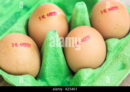 Four brown Dutch eggs in a green egg box with the focus on one of the egg codes Stock Photo