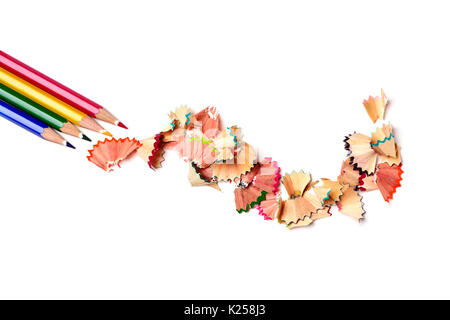 high-angle shot of a pile of pencil crayons of different colors and a pile of fan-shaped shavings of different colors on an off-white background Stock Photo