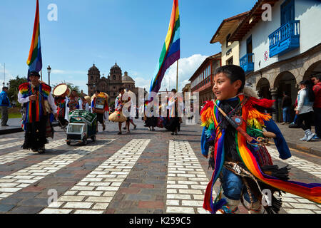 Small boy in indigenous costume in parade, and rainbow flags of Cusco, Plaza de Armas, Cusco, Peru, South America Stock Photo