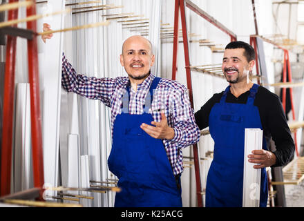 Two positive male workers inspecting PVC manufacturing output in workshop Stock Photo
