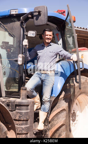portrait of joyful smiling mature male farmer near huge tractor Stock Photo