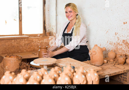 Smiling young woman making pot using pottery wheel in studio Stock Photo