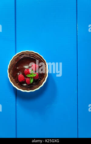 Chocolate raspberry tarts mint leaves on blue background Stock Photo