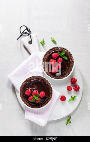 Chocolate raspberry tarts mint leaves on white marble board Stock Photo
