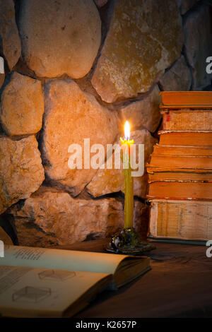 studying of sciences from books by the light of from the burning wax candle, selective focus Stock Photo