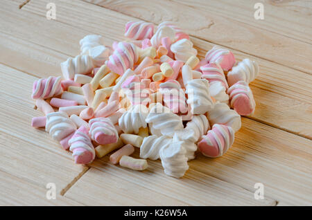 Multicolored marshmallows on bright wooden table. Background of multi-colored and different in shape and size of marshmallows. Sweets background Stock Photo