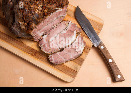 A juicy fresh baked pork with herbs and spice on wooden cutting board. Country style sliced oven-baked spicy ham. Stock Photo