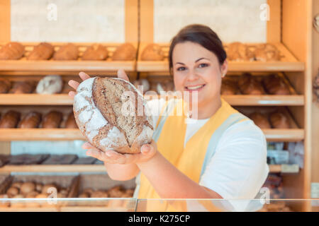 Saleslady in bakery shop presenting bread  Stock Photo