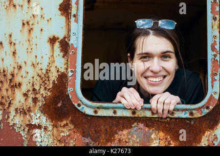 Attractive young woman looking out of the window metal caboose. Stock Photo