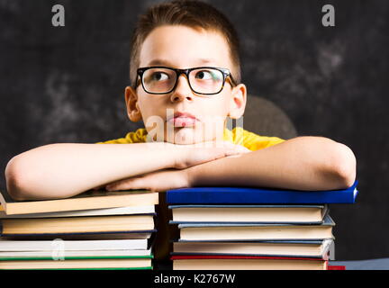Boy taking a rest on top of piled books Stock Photo