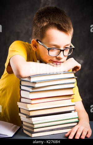 Boy taking a rest on top of piled books Stock Photo
