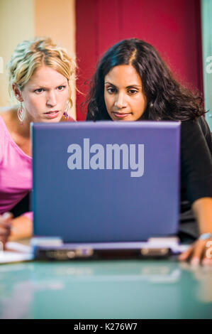Two young business professionals working together with a laptop computer. Stock Photo