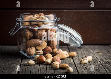 Different types of nuts in the nutshell. Hazelnuts, walnuts, almonds, pecan nuts and pistachio nuts on old wooden table. Stock Photo