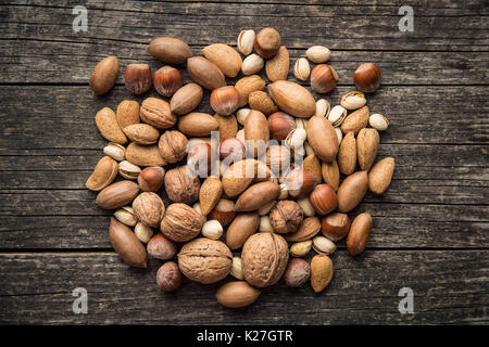 Different types of nuts in the nutshell. Hazelnuts, walnuts, almonds, pecan nuts and pistachio nuts on old wooden table. Stock Photo